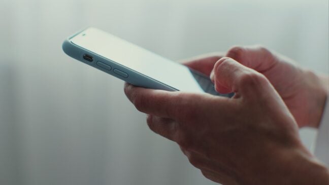 A hand holding a smartphone, ready to tap on the screen